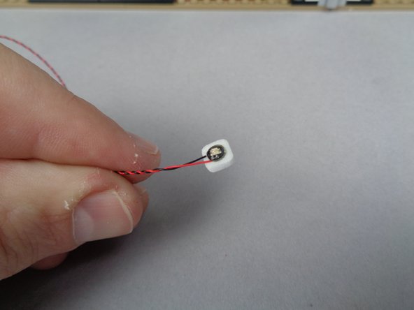 As shown in the third photo for this step, place a sticky square on the back side of the green Pico LED light.