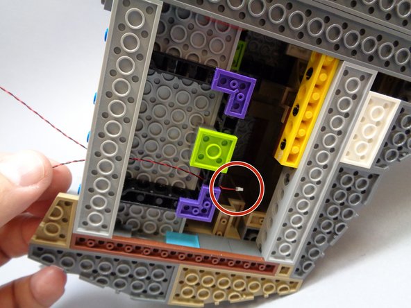 As shown by the red circle in the first photo, pull the lantern wire all the way through the hole in the Technic brick so the lantern wire is tight.