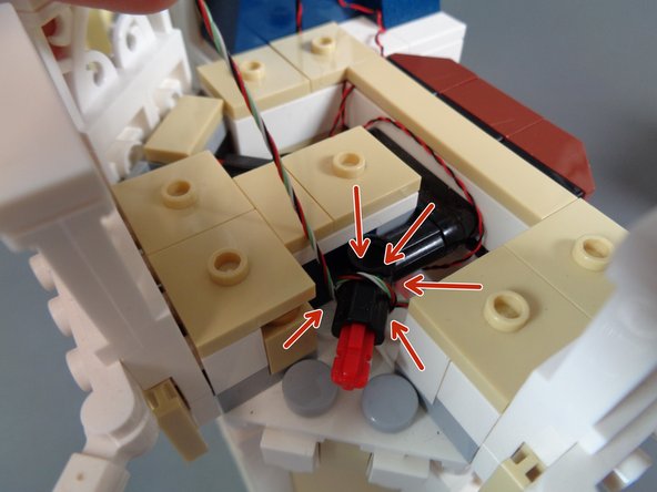As shown by the red arrows in the second photo, wrap the wire once around the black Technic bracket.  This will provide strain relief for the wire and help hold it in place.