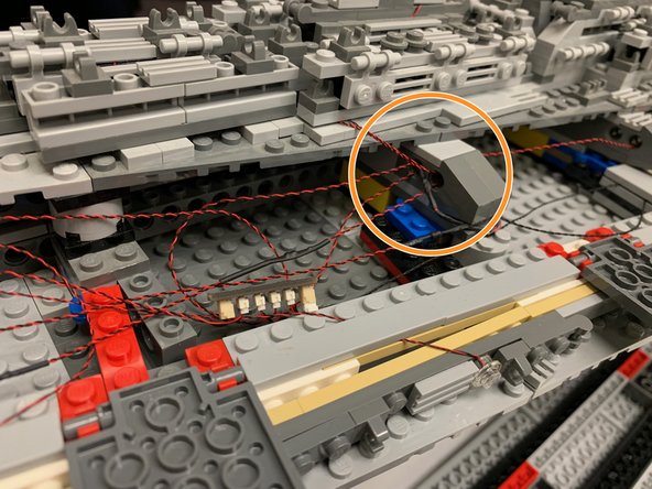 The photos in this step show how you can hide the light wires inside the open parts of the ship.  The light wires have plugs that are small enough to fit through Technic brick holes (see the orange circle in the first photo), so you can use open holes to coil extra wire.