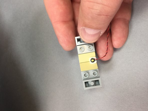 As shown by the red circle in the third photo, route the light wire towards the back of the Falcon and hold it in place with the dark tan tile.