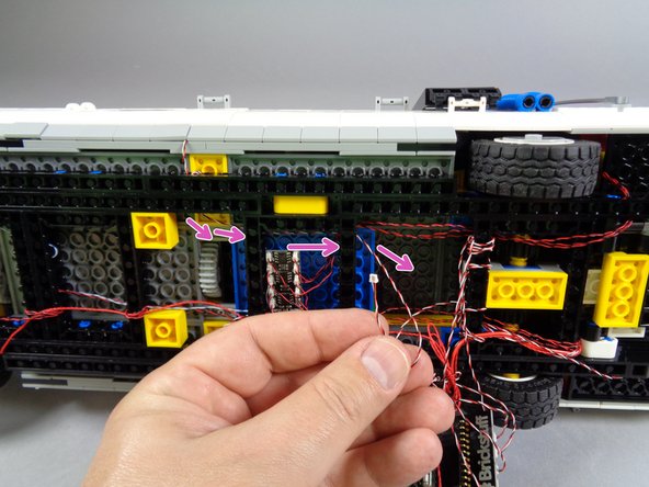 Pass the wire through one more black Technic beam toward the main controller.  The purple arrows in the second photo show the path the door switch wire should take.