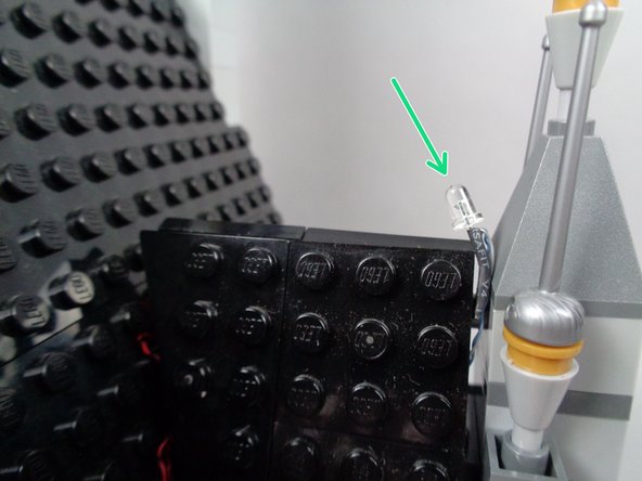 As a final check before proceeding, look at the lightning LED light as shown by the green arrow in the third photo for this step.  Make sure it is still angled back toward the mansion, and adjust if needed by gently bending the LED.