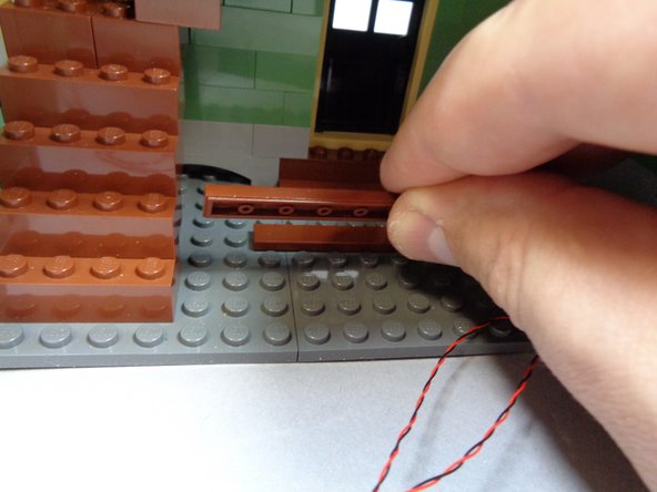 As shown in the third photo, run the two fireplace light wires along the floor and back toward the staircase.