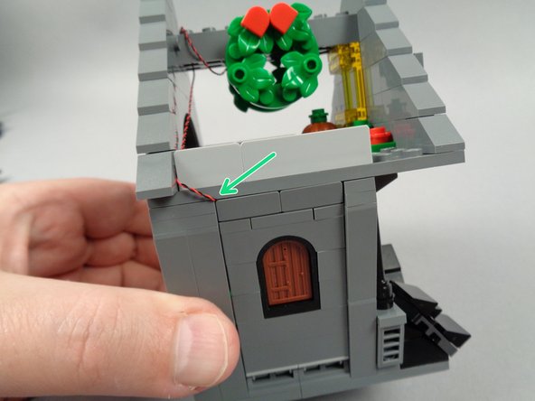 The green arrow in the second photo for this step shows how the attic light wire should look after snapping the wall section back into place.