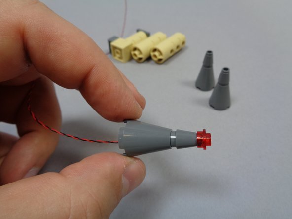 There should be three transparent red round 1x1 LEGO plates in Bag 8.  Place one on top of each small tower roof, on top of each light as shown in the first and second photos.