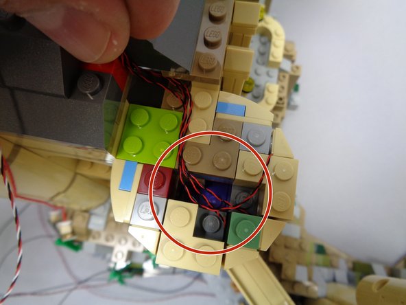 As shown in the first photo, carefully gather the three light wires and route them out the back of the tower top as shown.