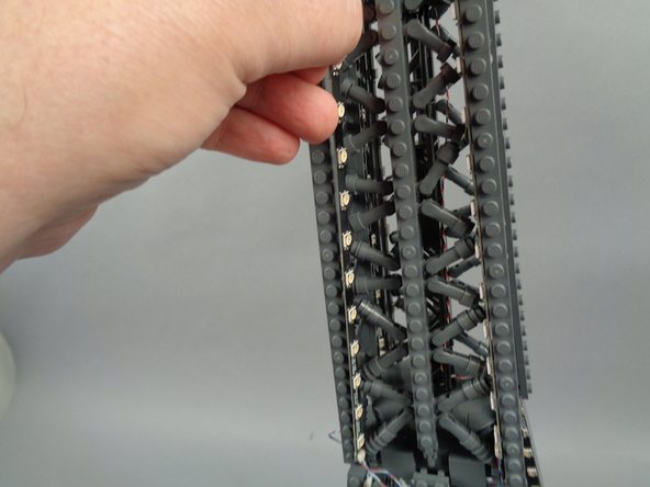 As shown in the photos for this step, attach the top of strip #2 to the tower frame, and re-position brace elements as needed to make room for the LED lights and strip.