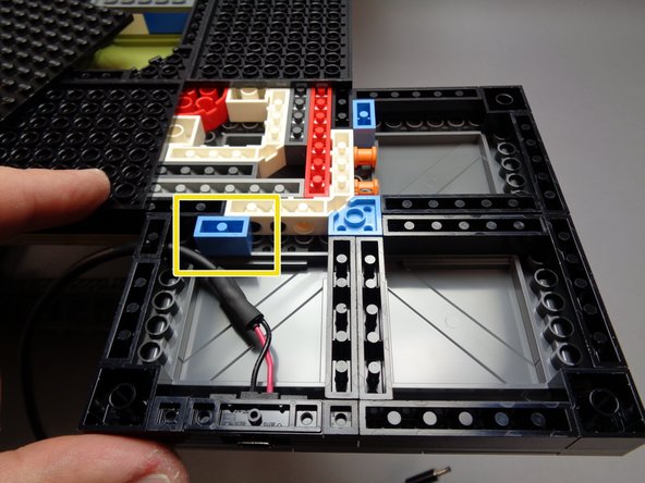 As shown by the yellow rectangle in the first photo for this step, there is a 1x2 blue brick that may have remained attached to the large black base plate when you removed it.  You can re-attach this blue brick in the location shown, next to the power wire.