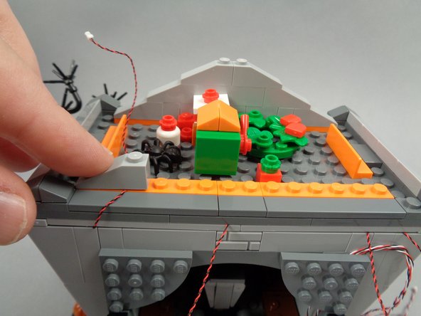 As shown in the third photo for this step, re-attach the leftmost roof frame slope to hold the wire in place.