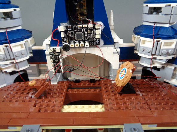 As shown in the second and third photos for this step, you should now have the four tower lights connected to the BRANCH09X adapter.  You will have excess wire and you can coil the extra wire using a pencil or tweezers so the wiring is neat.