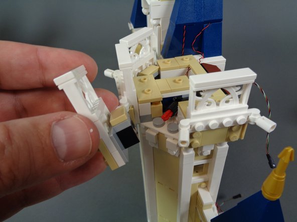 As shown in the first photo for this step, remove the white fence section from the front left side of the top of the middle castle section.