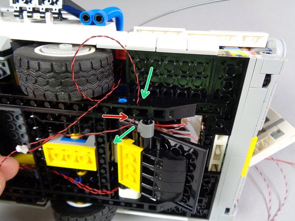 Next you will pass the two light wires through the hole in the black Technic frame shown by the blue circle in the first photo for this step.