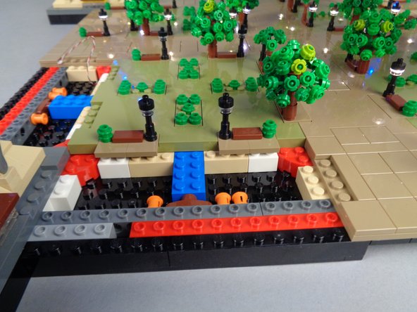 If the two lamp posts shown by the orange boxes in the first photo for this step separated along with Panel 4L, you will need to re-position them onto the large center Panel 4 as shown in the second and third photos.