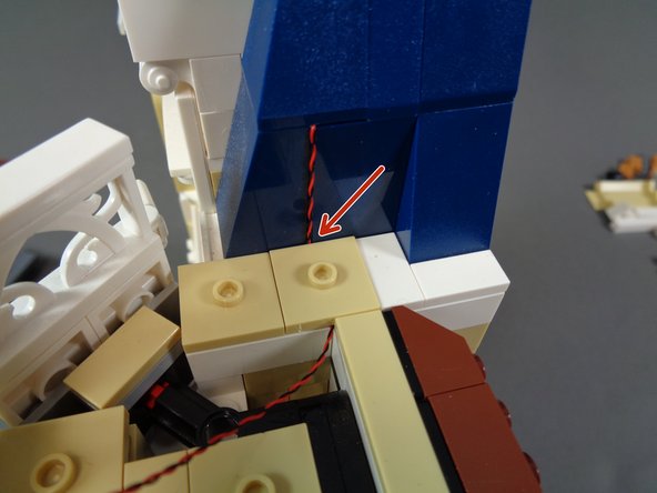 As shown in the second photo, remove the 2x2 tan LEGO jumper plate and run the light wire between, not on top of, the studs underneath.