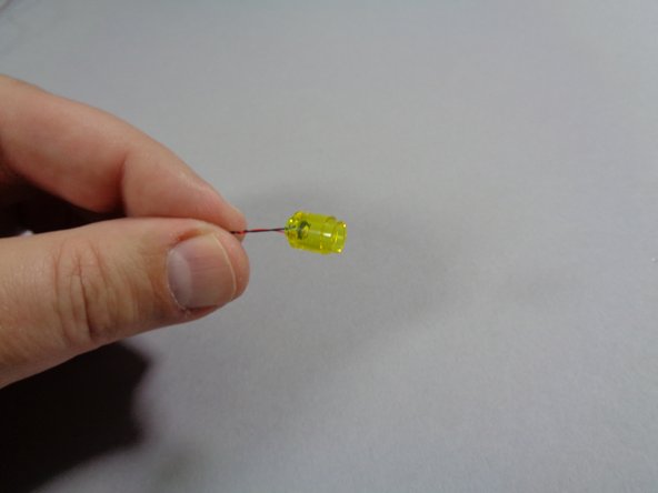 As shown in the second photo, feed the LED light plug through the large hole of the round LEGO brick so the small white plug comes out the small hole of the brick.  This should allow the LED light to slide inside the transparent yellow brick as shown in the third photo.