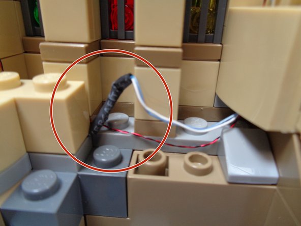 The wires should run toward the rear of the slope piece, inside the &quot;channel&quot; created by removing the light blue plates.  Wires should not run under the studs on the front of the tan slope pieces.