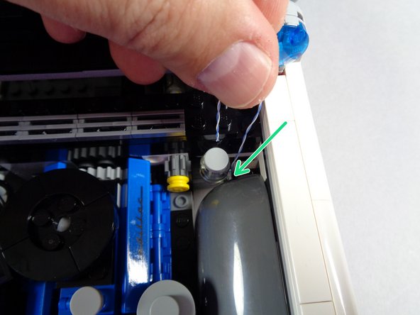 As shown by the green arrow in the first photo for this step, pass the plug for the hood spot light wire down behind the front wheel of your Ecto-1.