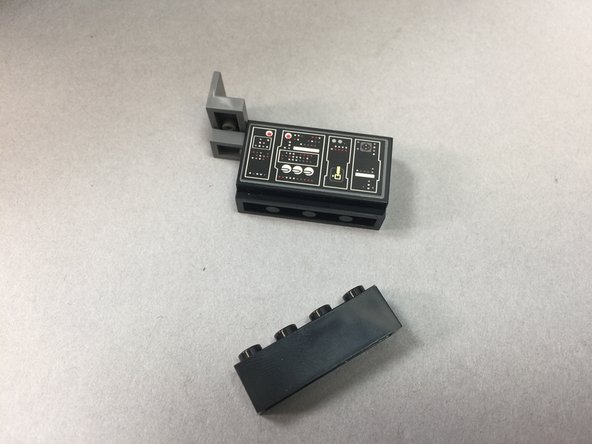 As shown in the third photo, remove the 1x4 black brick from the bottom of the computer panel assembly.