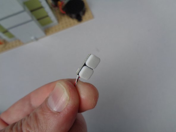 As shown in the second photo for this step, attach two sticky squares to the back side of the magnetic switch.