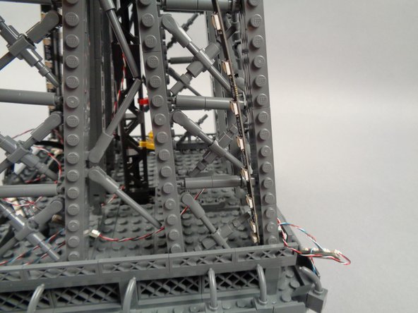 Remove the backs of the sticky dots on the first light strip (connected to plug #1 of the adapter board), and attach the strip to the tower frame as shown in the photos for this step.
