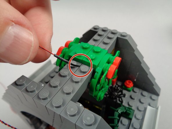 As shown in the first photo for this step, replace the second roof cross-beam, making sure the LED light wire passes up and between the beams as shown by the red circle in the second photo.