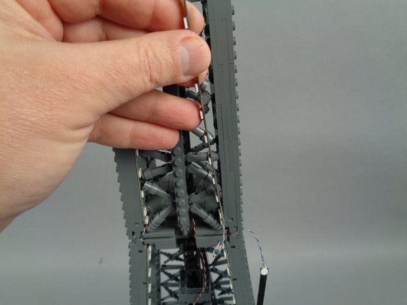 As shown in the photos for this step, attach the top of strip #1 to the tower frame, and re-position brace elements as needed to make room for the LED lights and strip.