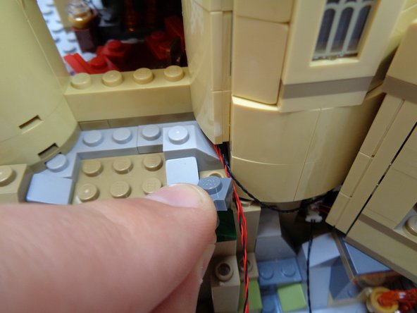 Replace the dark bluish gray clip, and as shown by the blue rectangle in the third photo, wrap the red and black control wire around the clip and re-attach the tree to hold the wire in place.