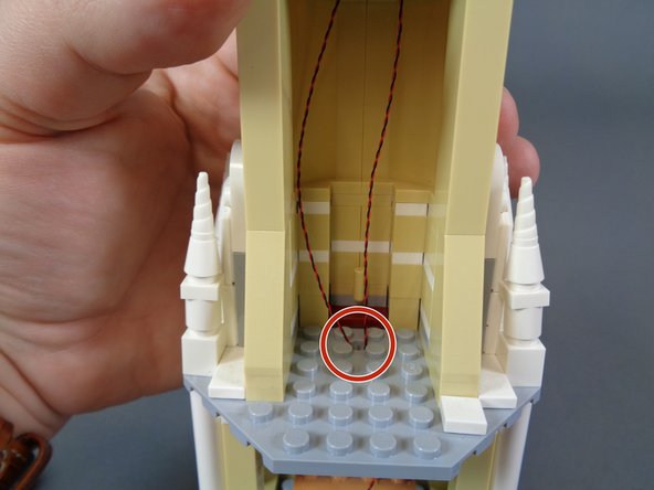 Run the two light wires through the circular hole in the floor of the mirror room as shown by the red circle in the second photo.