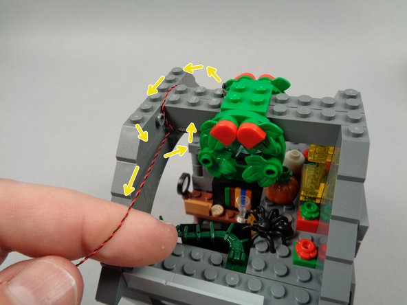 As shown by the yellow arrows in the first photo for this step, loop the LED light wire around the beams 1.5 times, so the wire passes under the beams and toward the back edge.