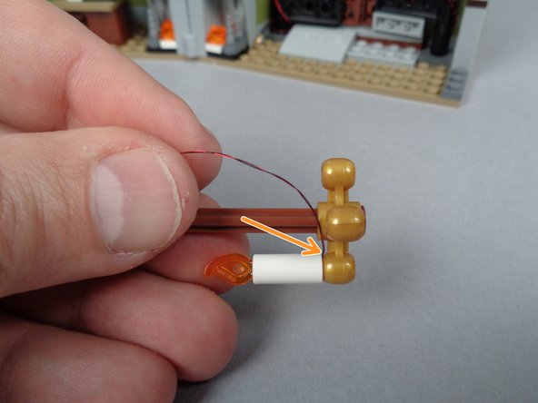 The first photo for this step shows one candle fully inserted into the gold frame, with the orange arrow showing how the LED light wire passes up toward the top of the candle.