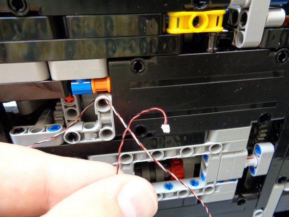 As shown in the second photo, bending the wires a little makes it easier to route them through the hole in the Technic bracket shown by the red circle in the third photo.