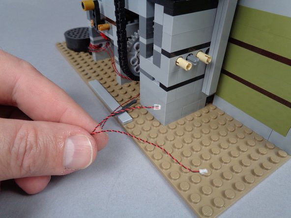 As shown in the first photo for this step, pull both candle light wires all the way through to the back side of the mansion.