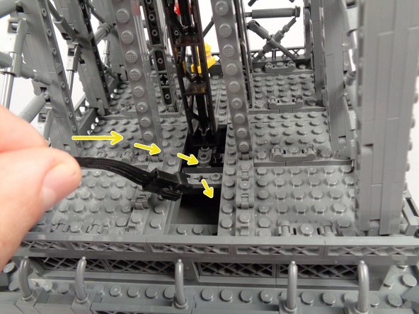 As shown by the yellow arrows in the first photo for this step, pass the large plug of the inter-level connecting board down through the opening you made by removing the two plates.
