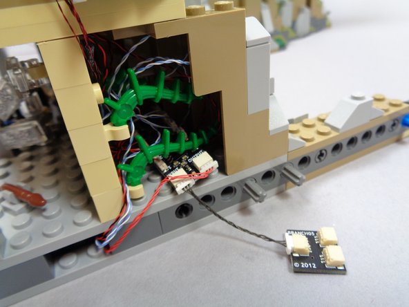 As shown in the third photo, re-attach the two green plant pieces.  These should help keep the BRANCH09X board and light wires inside the space behind the Chamber of Keys room.