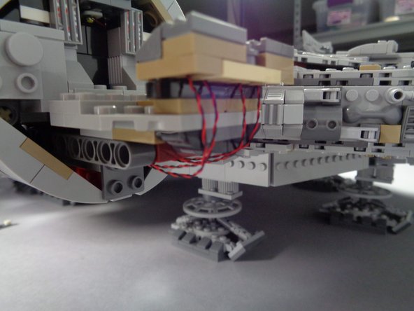 As shown in the first and second photos for this step, re-attach the cockpit control panel section to the Falcon frame.
