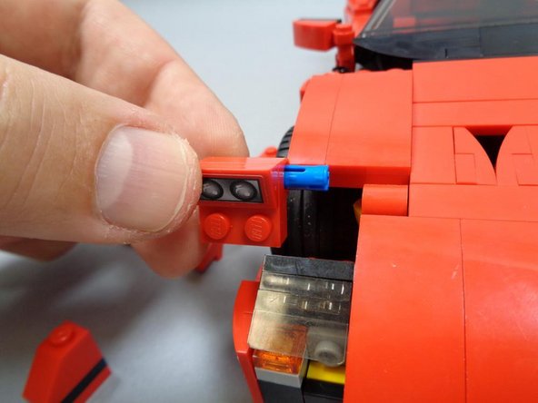 Carefully remove the left and right headlight assemblies, making sure the blue Technic pins remain inserted into the headlight sections.