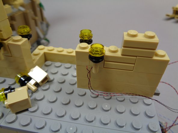 As shown in the third photo, replace the two torches on the right side of the arch with one of the pre-lit &quot;Y&quot; torch assemblies.  Run the torch wires down and to the right, toward the castle edge.