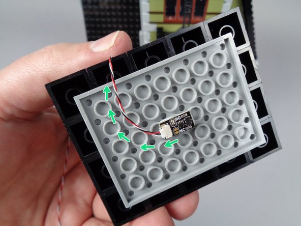 As shown by the green arrows in the first photo for this step, bend the wire for the magnetic switch so it passes out the back side of the pyramid roof top section.