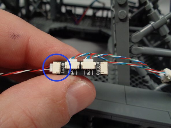 Take the final light strip pair with connected adapter board and, as shown by the blue circle in the photo for this step, connect the end of the control cable coming from the third adapter board to the INPUT plug on the fourth adapter board.