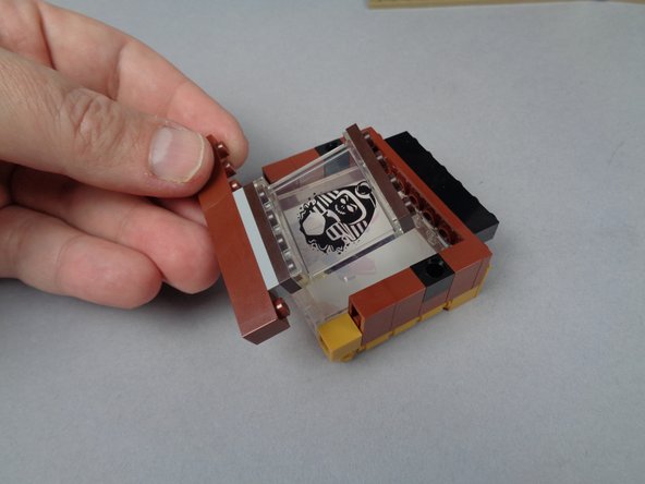 As shown in the photos for this step, disassemble the back side of the explorer painting so you can remove the panel with the Sphinx and the brown brick underneath it.