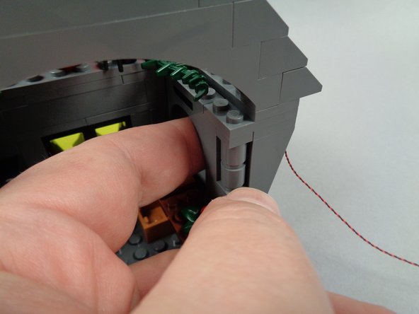 As shown in the second and third photos for this step, gently press with your finger on the side of the house (behind where the blackboard was mounted) so the side of the house tilts outward.