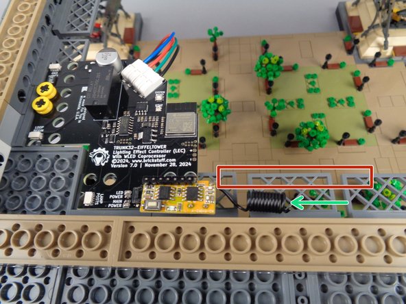 As shown by the green arrow in the photo for this step, carefully bend the antenna wire slightly so it runs parallel to the inner edge of the tower frame, away from the receiver board.