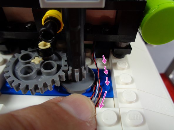 As shown by the green arrows in the second photo for this step, re-attach the two rear blue roof lights, making sure the wires for their lights pass between the clip fingers and that the wires are not pinched.