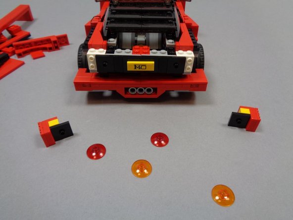 As shown in the first photo, remove the large orange and red transparent LEGO® dishes from the rear of the car.