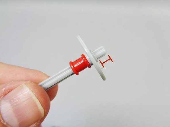 Using one of the light bluish gray Technic axles provided with the lighting kit, attach one of the light bluish gray discs from the original kit, and add the red bushing below it.