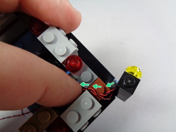 As shown in the first photo for this step, position the light stack with wires coming out the left side on the right side of the marquee bottom.