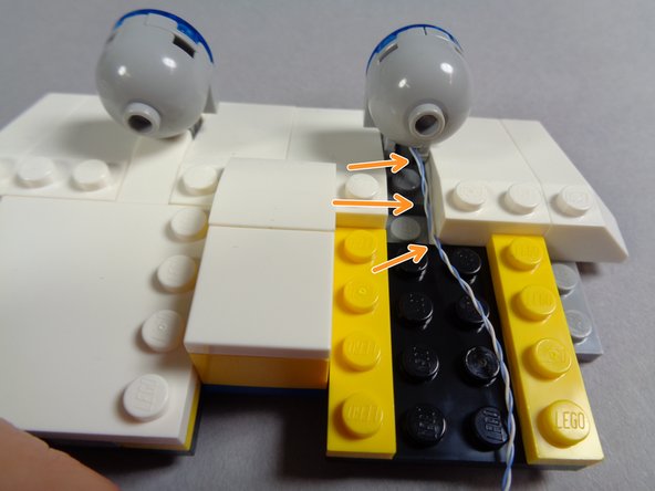 As shown in the first photo for this step, re-attach the first blue light to the front roof section.