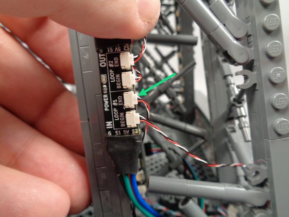 As shown by the green arrow in the second photo for this step, connect the control cable to the plug labeled END on the inter-level connecting board.