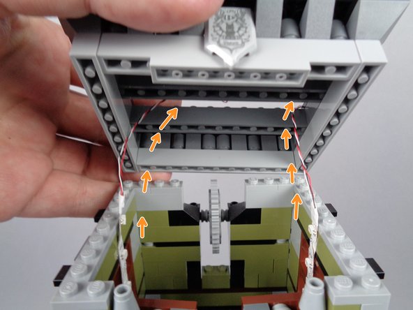 As shown by the orange arrows in the first photo for this step, pass both light strip wires through the center of the roof section you removed earlier, then carefully re-attach the roof.